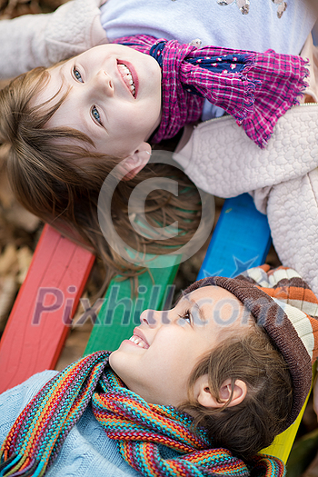 cutte little girl and boy in childrens park having fun and joy while playing in playground on autumn cloudy day