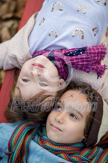 cutte little girl and boy in childrens park having fun and joy while playing in playground on autumn cloudy day