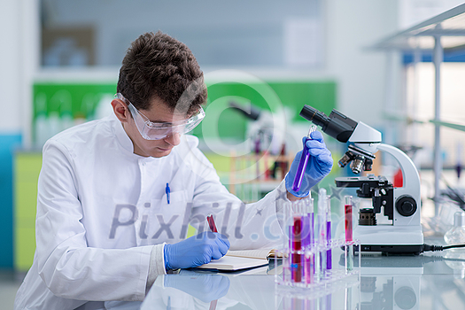 young student with protective glasses making chemistry experiment in bright laboratory,education and medicine concept