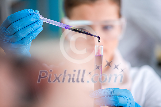 young female student with protective glasses making chemistry experiment in bright laboratory,education and medicine concept