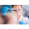 young female student with protective glasses making chemistry experiment in bright laboratory,education and medicine concept