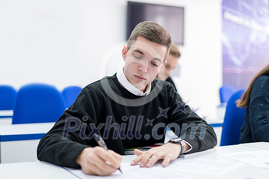 young male student writing notes in the classroom young male student writing notes in the classroom