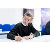 young male student writing notes in the classroom