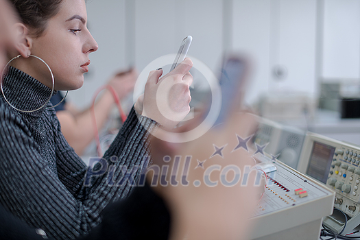 young female student using a mobile phone during the break in the electronics classroom