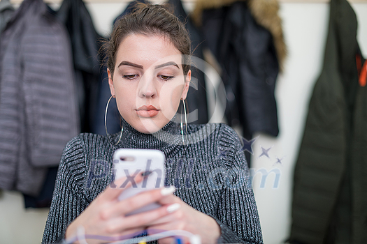 young female student using a mobile phone during the break in the classroom