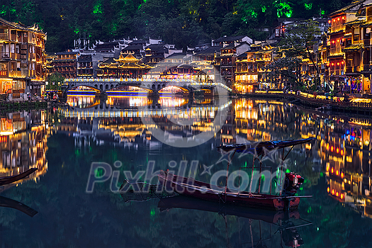 Chinese tourist attraction destination - Feng Huang Ancient Town (Phoenix Ancient Town) on Tuo Jiang River illuminated at night. Hunan Province, China