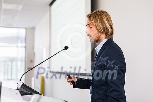 Handsome young man giving a speech at a conference