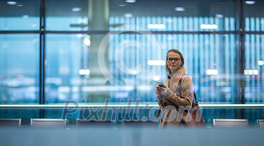 Young female passenger at the airport, using her tablet computer while waiting for her flight (color toned image) Young female passenger at the airport, using her tablet computer while waiting for her flight (color toned image)