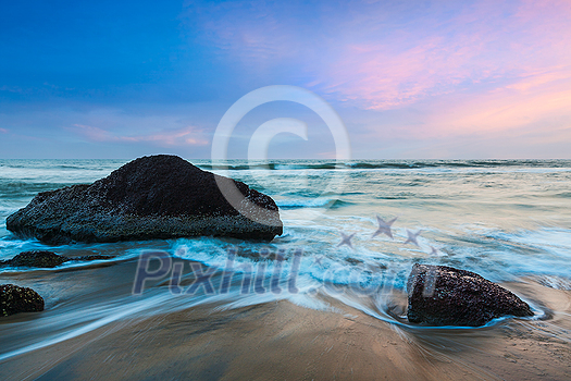 Tropical beach vacation background - waves and rocks on beach of sunset Tropical beach vacation background - waves and rocks on beach of sunset