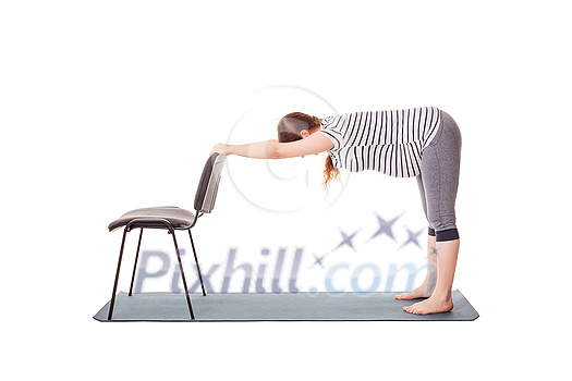 Pregnancy yoga exercise - pregnant woman doing yoga asana Uttanasana Standing Forward Fold Pose with hands on chair easy variation isolated on white background Pregnancy yoga exercise - pregnant woman doing yoga asana Uttanasana Standing Forward Fold Pose with hands on chair easy variation isolated on white background