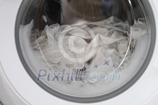 Close-up laundry running washing machine at home, amid a washing cycle, home electronics concept Close-up laundry running washing machine at home, amid a washing cycle, home electronics concept
