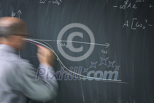 Math teacher drawing fuction graph on a blackboard during mathclass (motion blurred image) Math teacher drawing fuction graph on a blackboard during mathclass (motion blurred image)