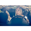 Middle aged woman at the steering wheel of her car, getting angry