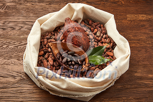 From above of white fabric sack filled with unpeeled cocoa beans and cocoa pods with green leaves From above of white fabric sack filled with unpeeled cocoa beans and cocoa pods with green leaves