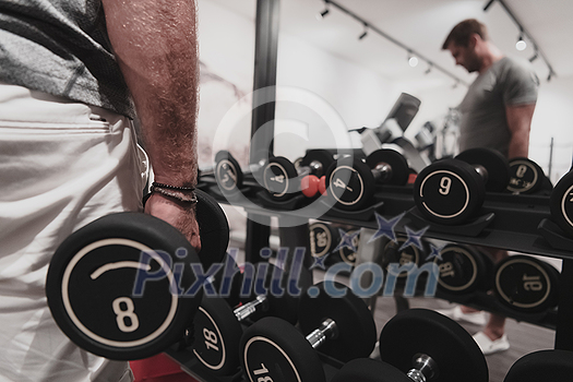 Struggling with age. Confident senior man exercising with dumbbells in the health club. Selective focus. High-quality photo Struggling with age. Confident senior man exercising with dumbbells in the health club. Selective focus. High-quality photo