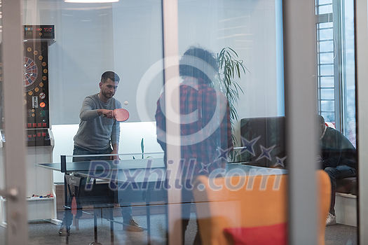 Two young start-up businessmen playing ping pong tennis at modern creative office space people group have meeting and brainstorming in background. High-quality photo Two young start-up businessmen playing ping pong tennis at modern creative office space people group have meeting and brainstorming in background. High-quality photo