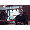 Young African American work in coworking space using smartphones analyzing online market trends, focused man worker reading financial news or browsing the internet on phone. Technology concept. High-quality photo