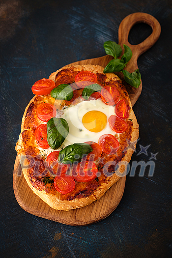 Homemade tasty pizza with egg, cheese, tomatoes and basil on dark background. Top view. Homemade tasty pizza with egg, cheese, tomatoes and basil on dark background. Top view.