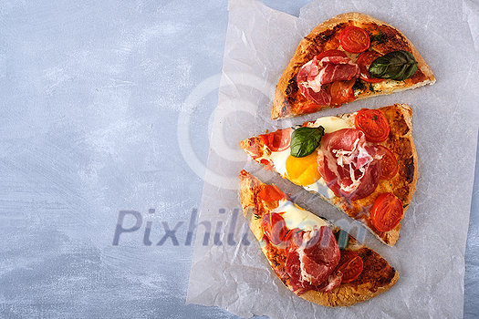 Sliced Homemade tasty pizza with bacon, egg, cheese, tomatoes and basil Sliced Homemade tasty pizza with bacon, egg, cheese, tomatoes and basil