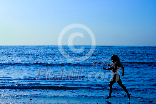 Female running along the beach at sunrise