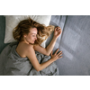 Pretty, young woman sleeping in her bed late in the morning on a weekend - compensating for the lack of sleep