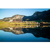 Amazing tranquil landscape with country area, houses and hills near the lake and reflection in clean blue water on a background of clear blue sky, Austria.