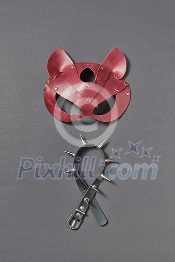 Set for erotic games - leather cat mask and black collar with sharp thorns on a black background, copy space. Sexual attribute for erotic games. BDSM Sex and erotic playing concept. Set for erotic games - leather cat mask and black collar with sharp thorns on a black background, copy space. Sexual attribute for erotic games. BDSM Sex and erotic playing concept.