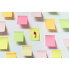 Red and white pharmaceutical pill on sticky note over white backdrop.