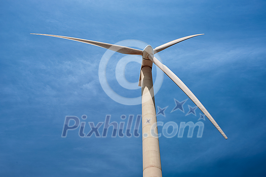Green renewable alternative energy concept - wind generator turbine generating electricity in blue sky Green renewable alternative energy concept - wind generator turbine generating electricity in blue sky