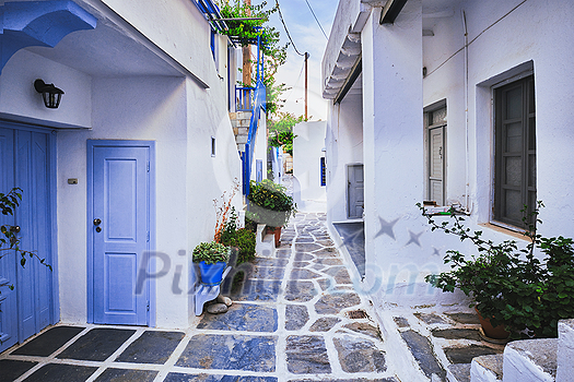 Picturesque narrow street with traditional whitewashed houses with blooming flowers of Naousa town in famous tourist attraction Paros island, Greece Picturesque narrow street with traditional whitewashed houses with blooming flowers of Naousa town in famous tourist attraction Paros island, Greece