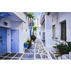 Picturesque narrow street with traditional whitewashed houses with blooming flowers of Naousa town in famous tourist attraction Paros island, Greece