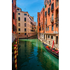 Narrow canal between colorful old houses with gondola boat in Venice, Italy