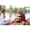 Couple in love enjoying picnic time drink and food in beautiful nature on the river bank