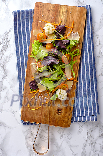 Healthy food. Fresh salad tomato, cheese and greens on the cutting board, top view. Healthy food. Fresh salad tomato, cheese and greens on the cutting board, top view.