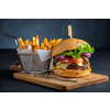 Tasty grilled beef burger with lettuce, cheese and onion served on cutting board with french fries on a black wooden table