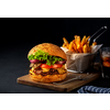 Tasty grilled beef burger with lettuce, cheese and onion served on cutting board on a black wooden table, with copyspace