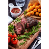 Juicy rare sliced grilled fillet steak served with tomatoes and cheese balls on an old wooden board. Top view. 