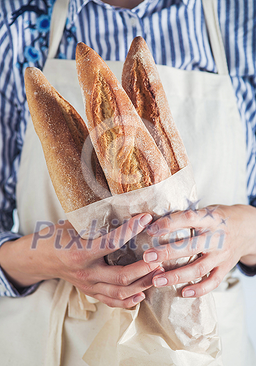 Close-up image of woman holding package of fresh baguettes