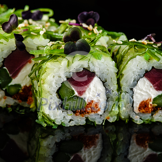 Close-up of traditional japanese sushi on a dark background with reflection. Roll with tuna and greens Close-up of traditional japanese sushi on a dark background with reflection. Roll with tuna and greens
